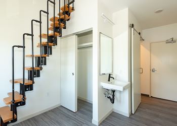 A white bathroom with a black metal staircase.